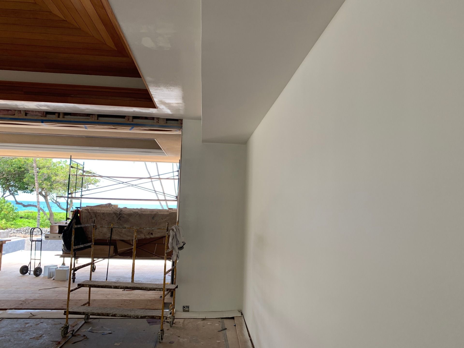 A room with a white wall and a scaffolding in the background.
