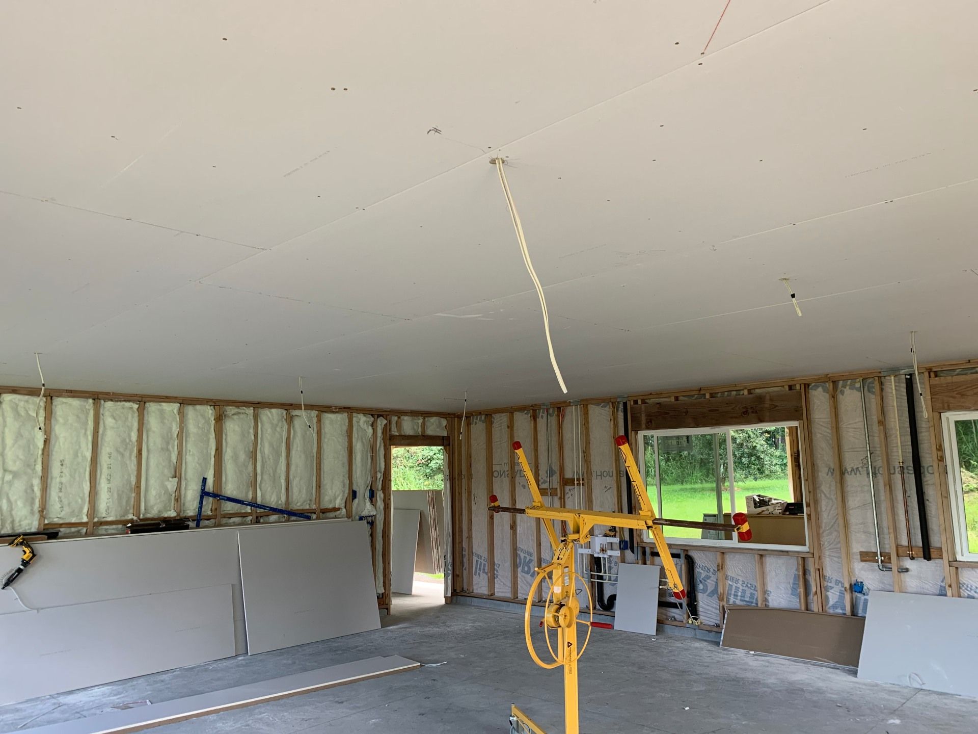 A large room with a ceiling that is being built and installed drywall.