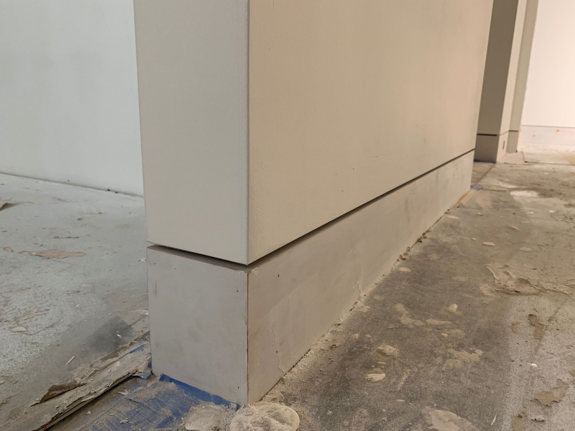 A white wall with a concrete base is sitting on a concrete floor.