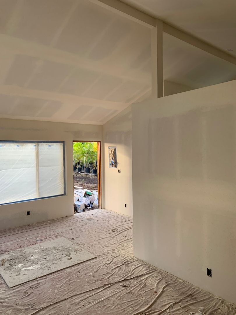 A living room with a lot of white walls and a window.