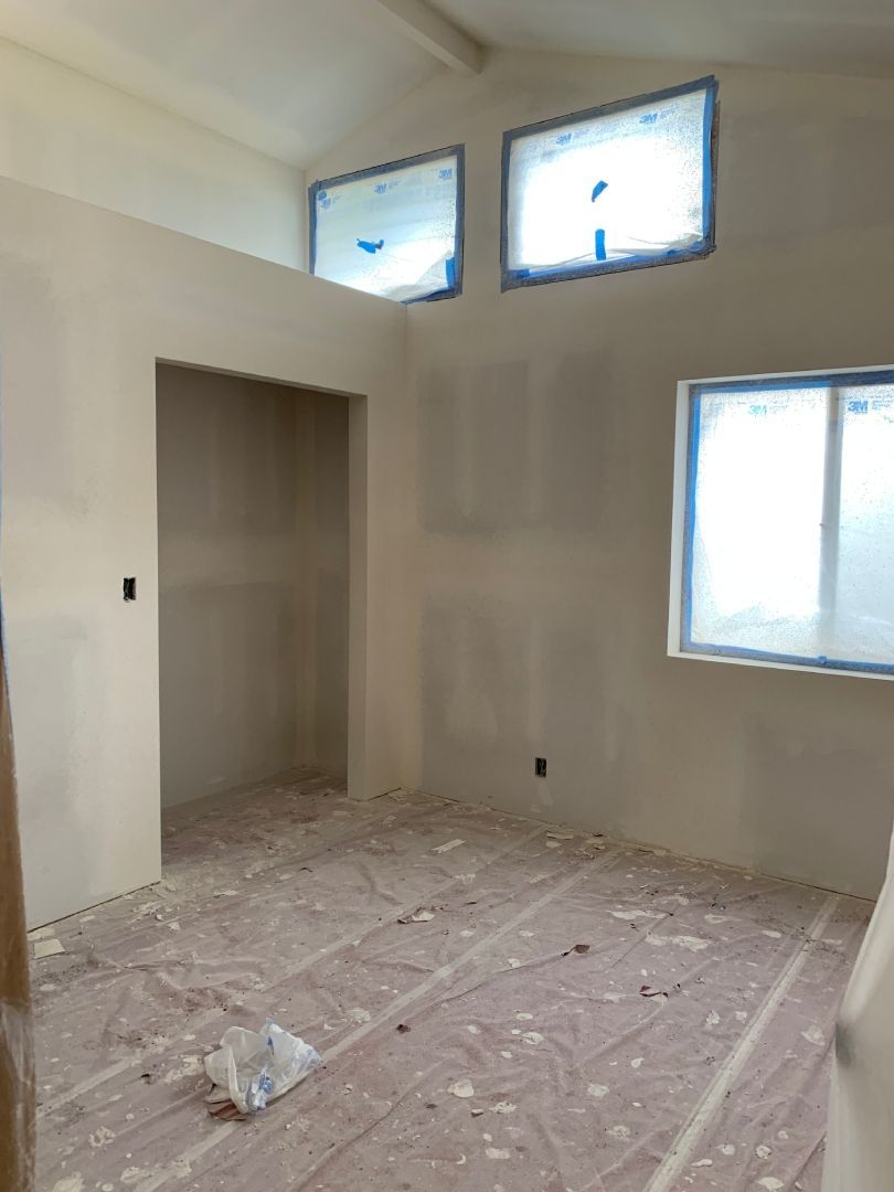 A room with a lot of windows and drywall being installed.