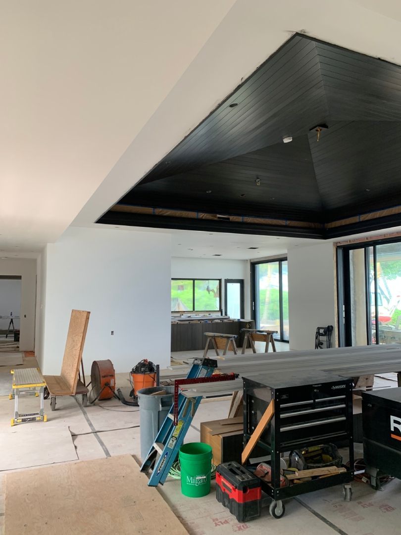 A large room with a table and a ladder in it with finished drywall.