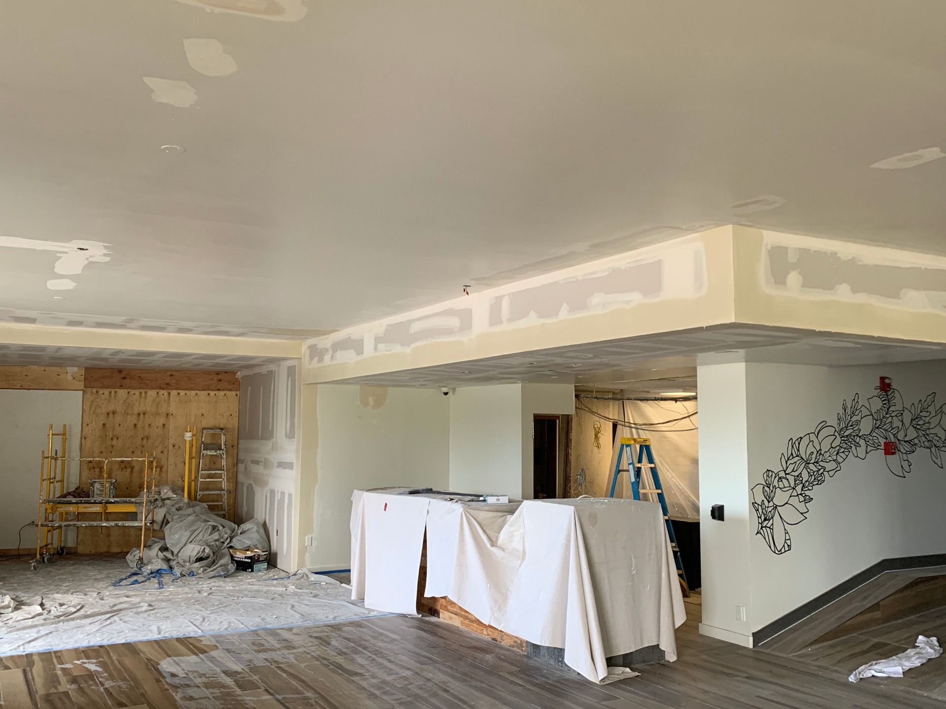 A large room with a drywall ceiling that is being remodeled.