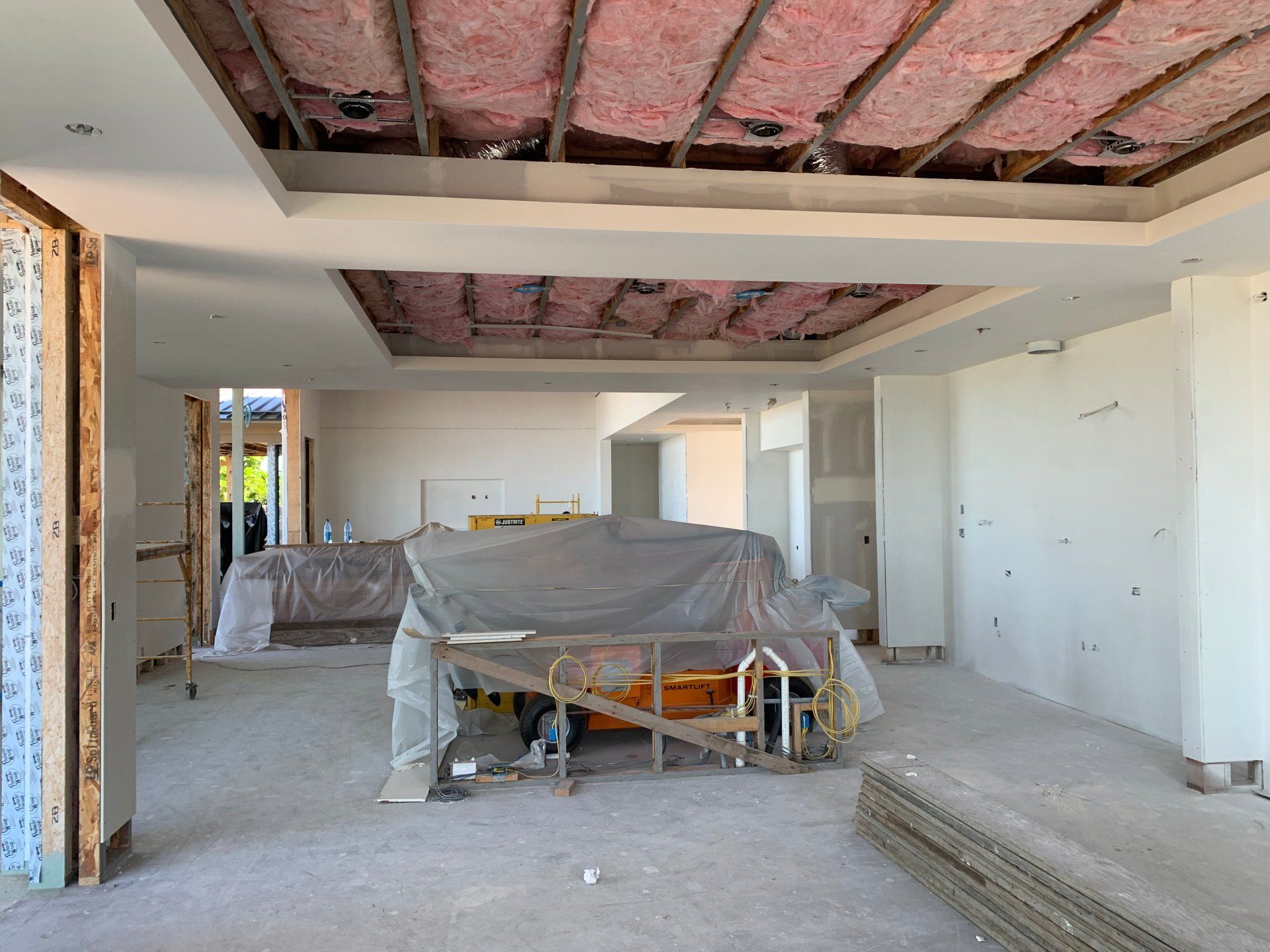 An empty room with and a ladder in it and drywall installation prep. 