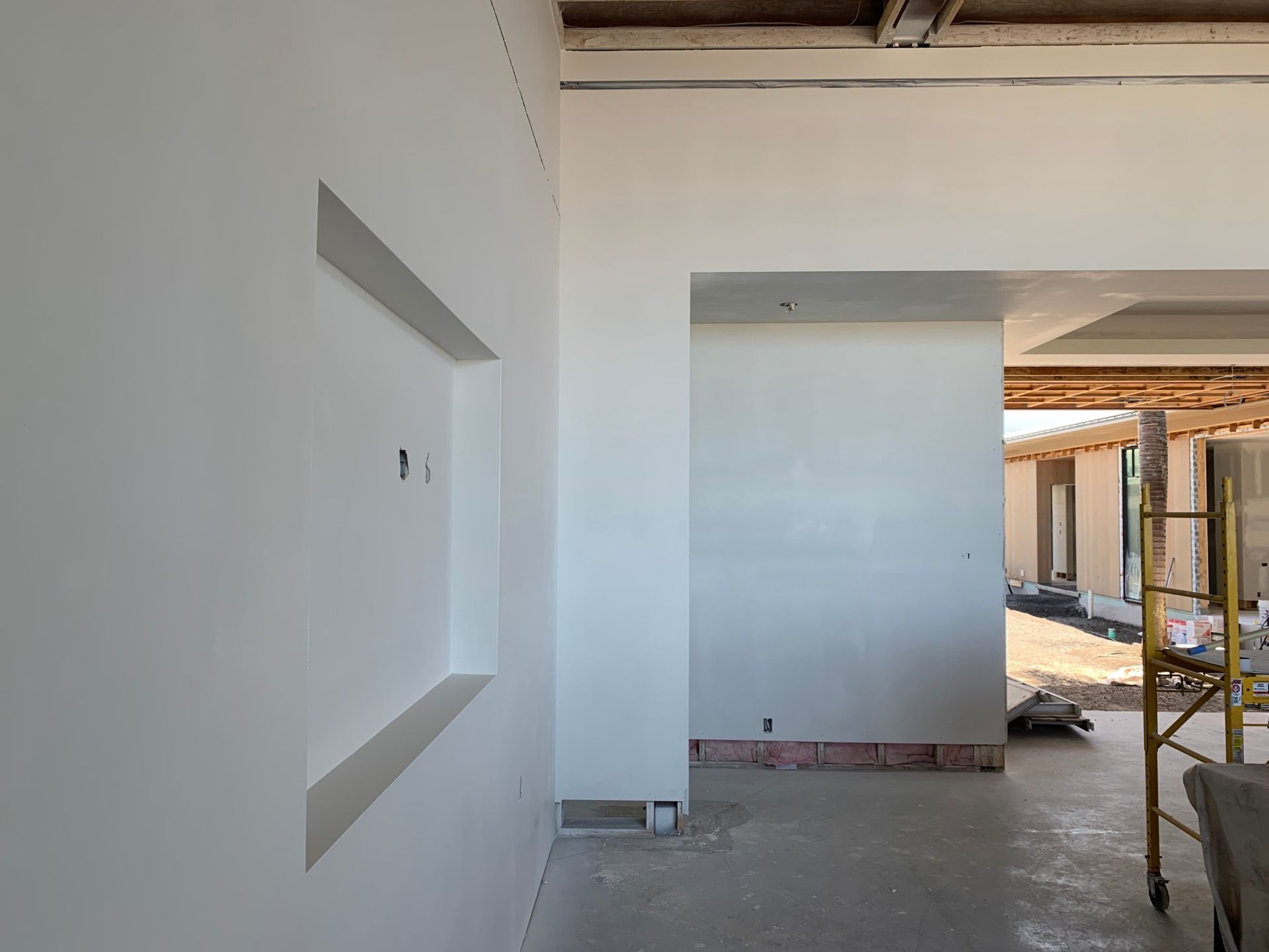 A building under construction with a scaffolding in the background and drywall completed/