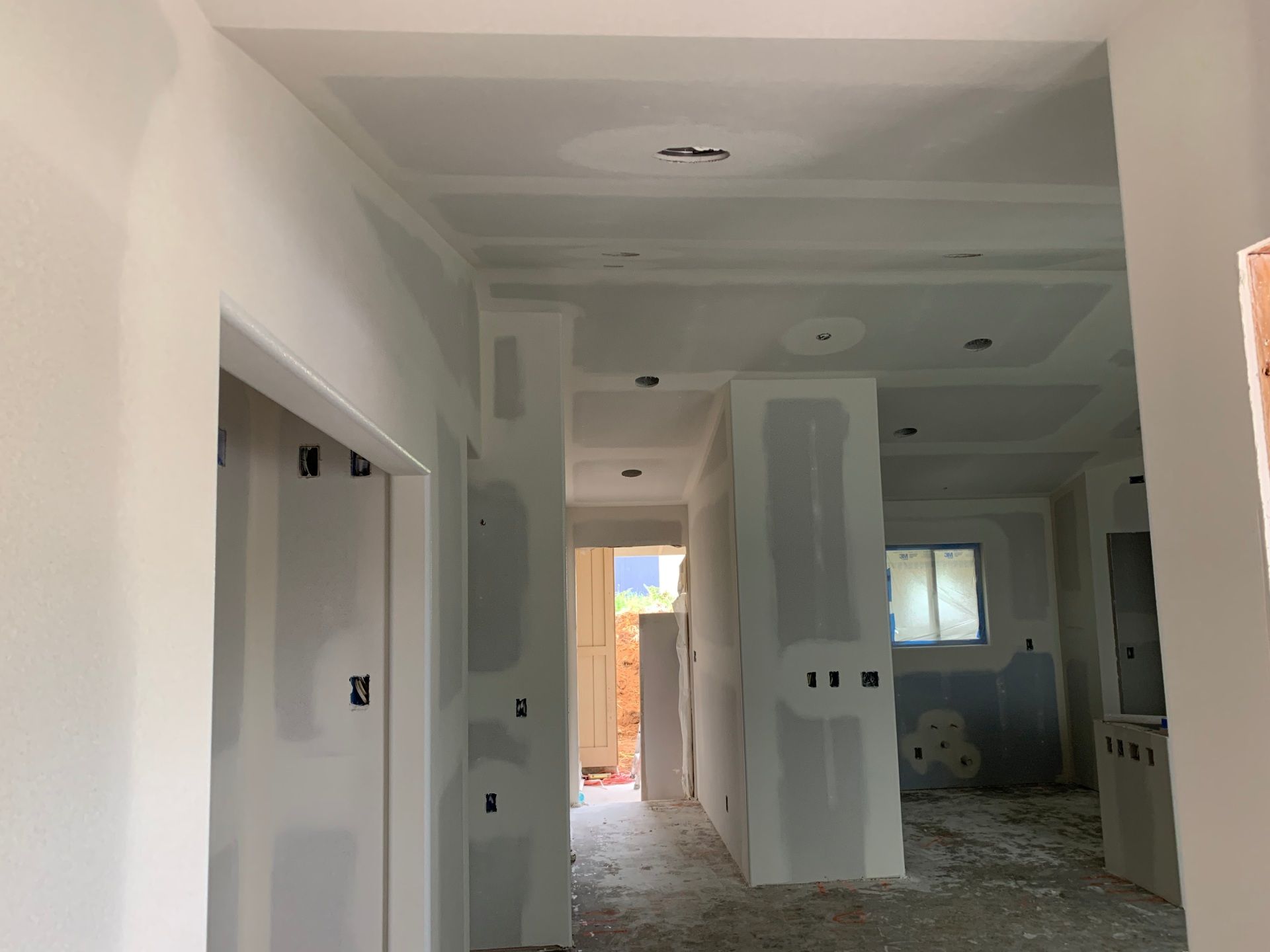 A hallway in a house under construction with drywall on the walls.