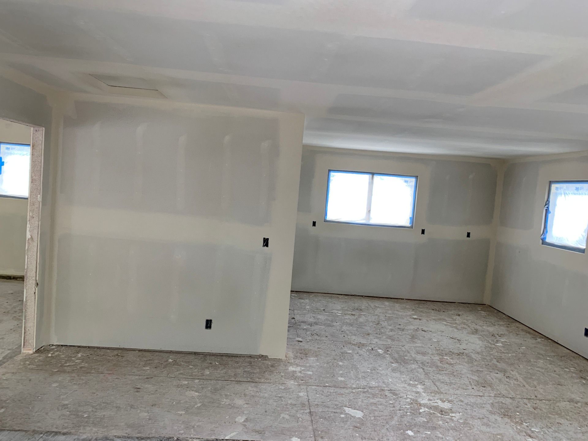 An empty room with a ceiling and a few windows and drywall installed. 