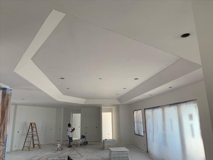 A man is drywalling the ceiling of a room in a house.