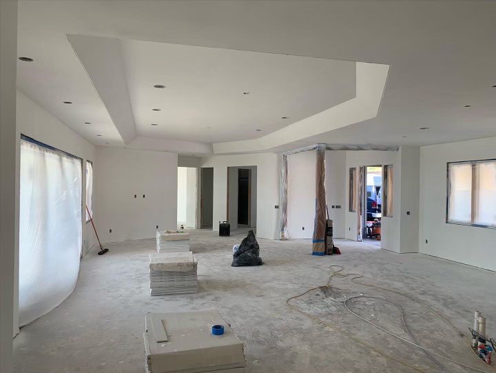 An empty room with drywall white walls and a vacuum cleaner on the floor