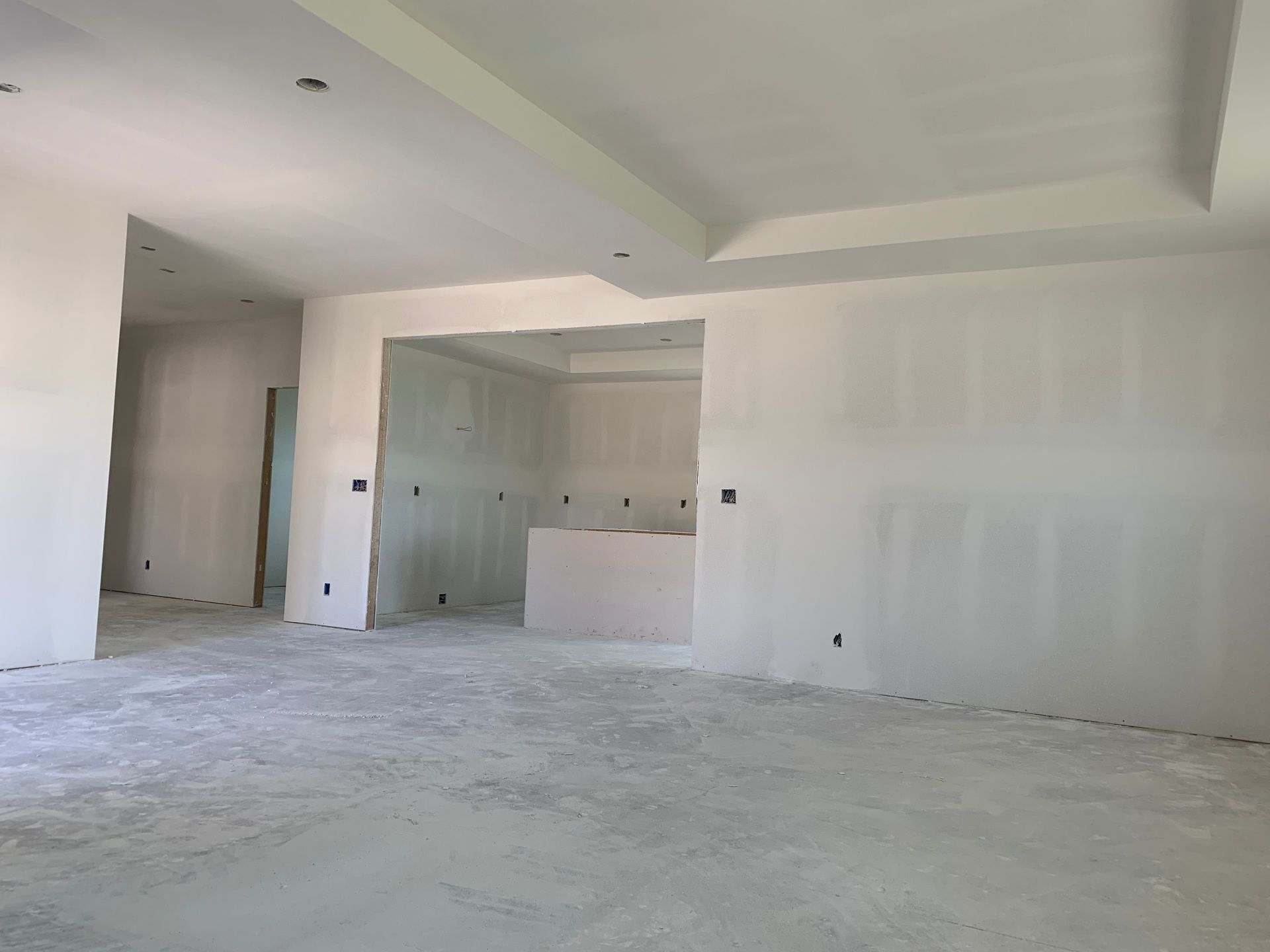 A large empty room with white drywall walls and a concrete floor.