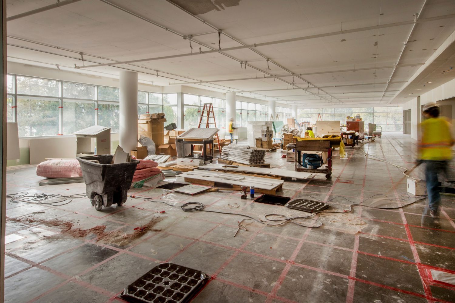 A large room is being remodeled and a man is walking through it.