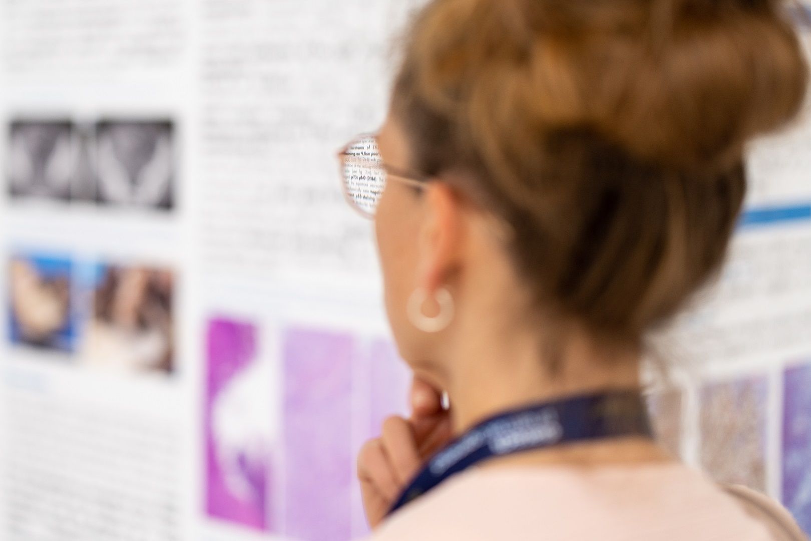 auf Jahrestagung der DGPatho 2022 betrachtet eine Frau aufmerksam ein wissenschaftliches Poster, das Text und Bilder enthält