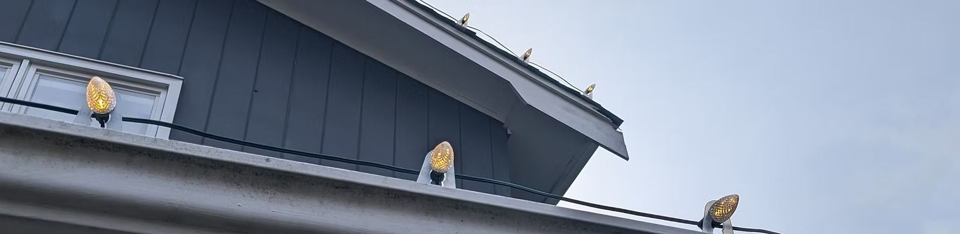 Building roof with golden decorative elements against a light blue sky.