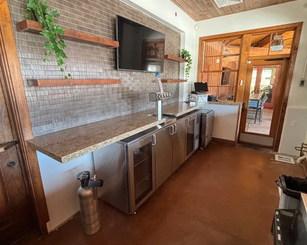 Bar area with granite countertop, stainless steel cabinets, and a brick-look wall.