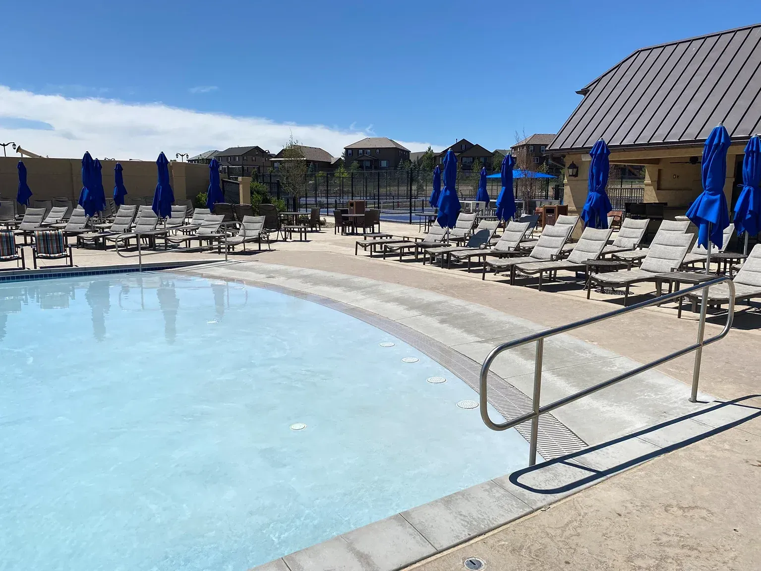 Pool with lounge chairs and umbrellas under a sunny sky.