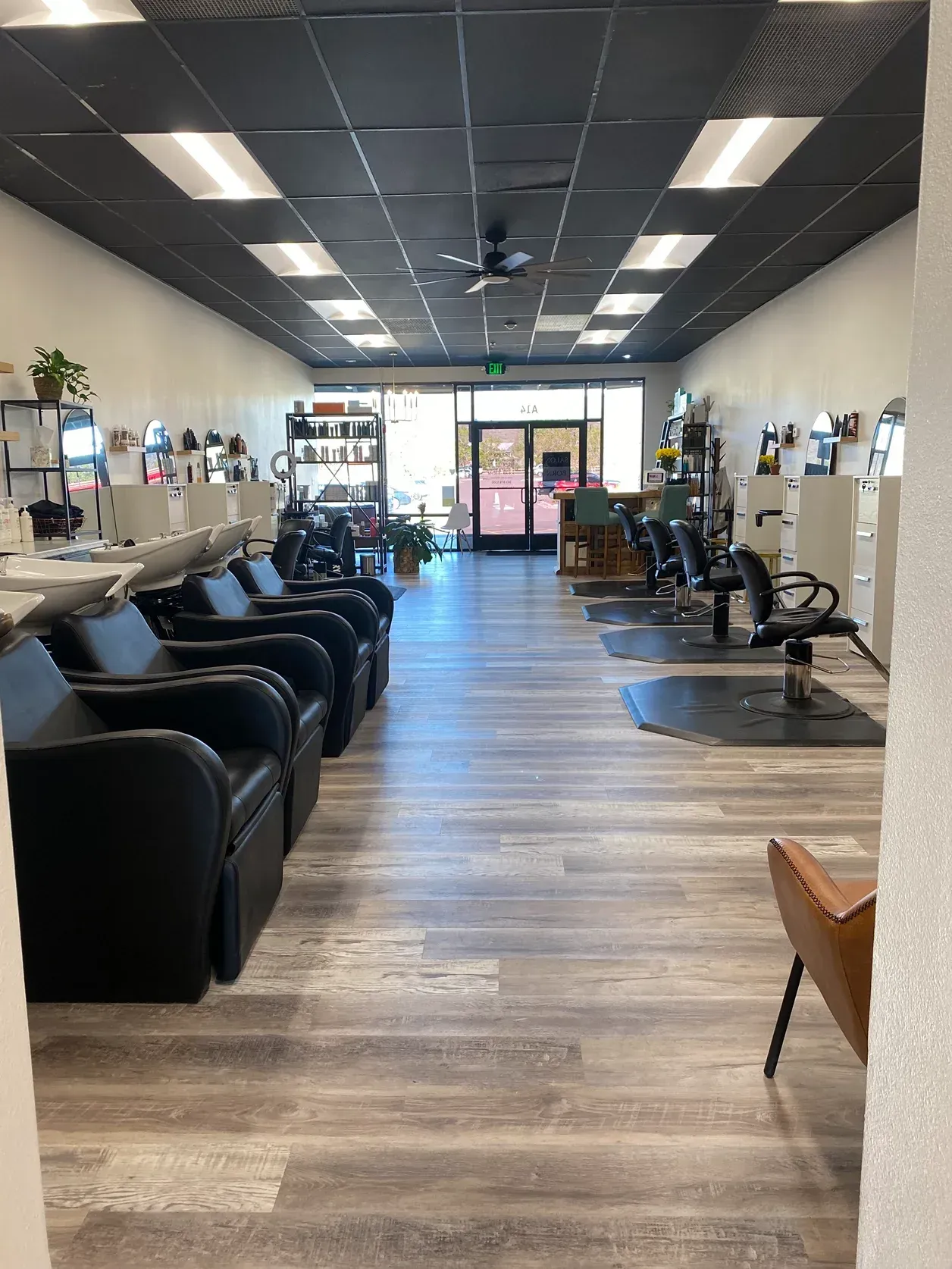 Interior of a hair salon with chairs, stations, and a dark ceiling.