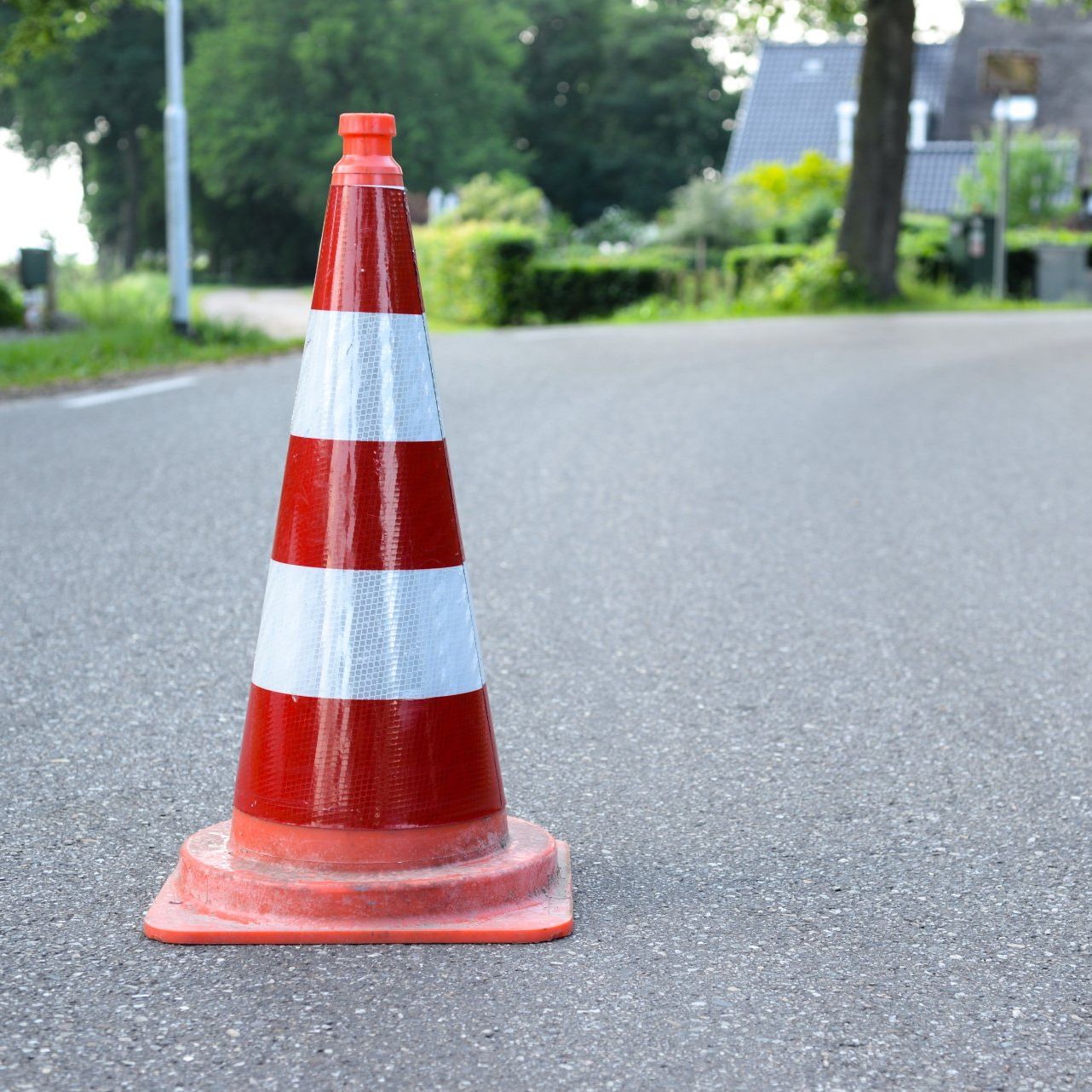 A red and white traffic cone is on the side of the road
