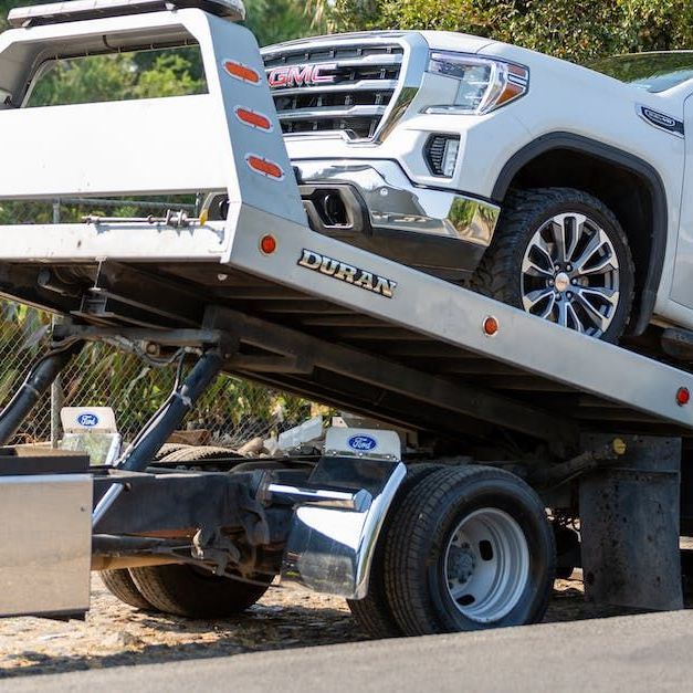 A gmc truck is being towed by a tow truck