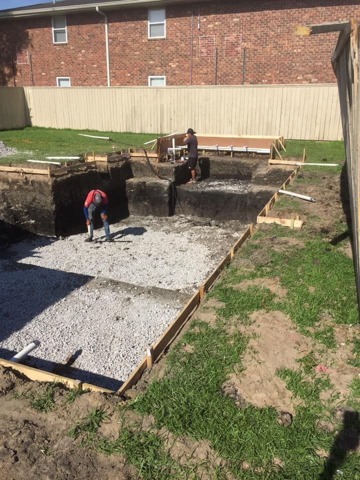 A man is working on a construction site in front of a brick building.