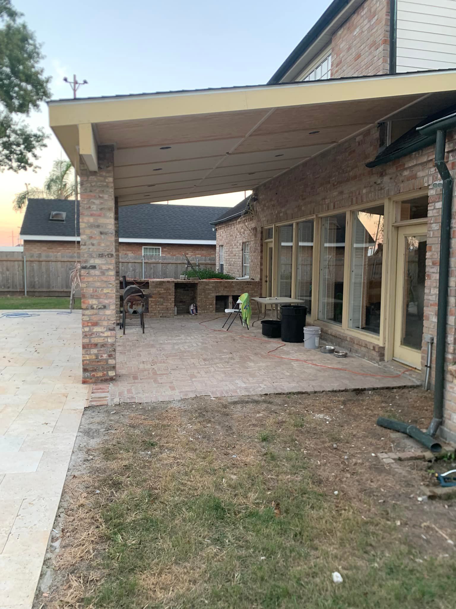 A brick house with a covered patio in front of it.