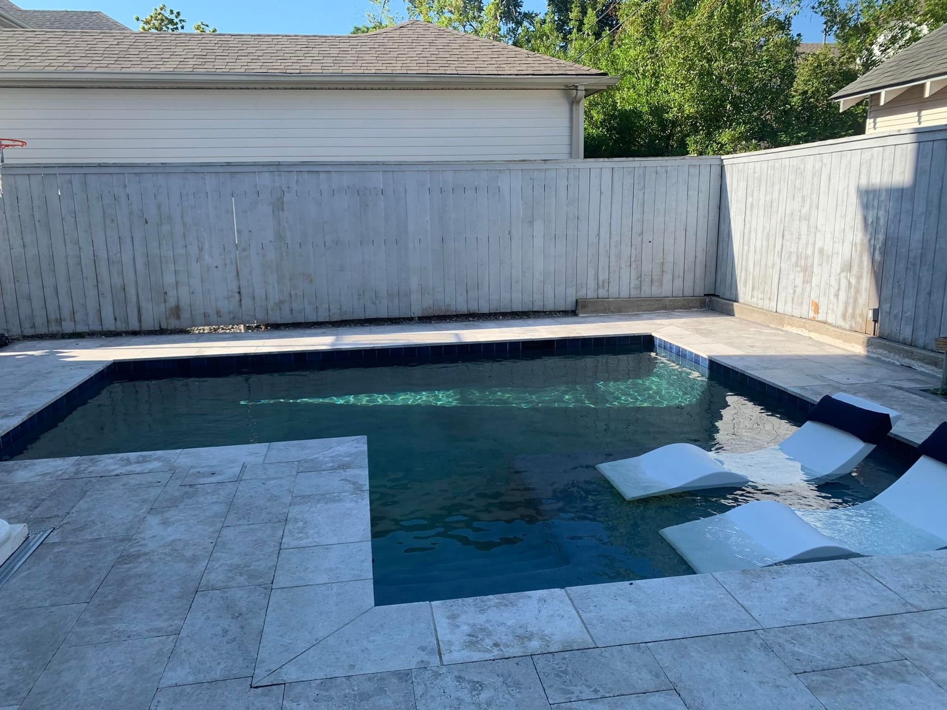 A large swimming pool is surrounded by a white fence.