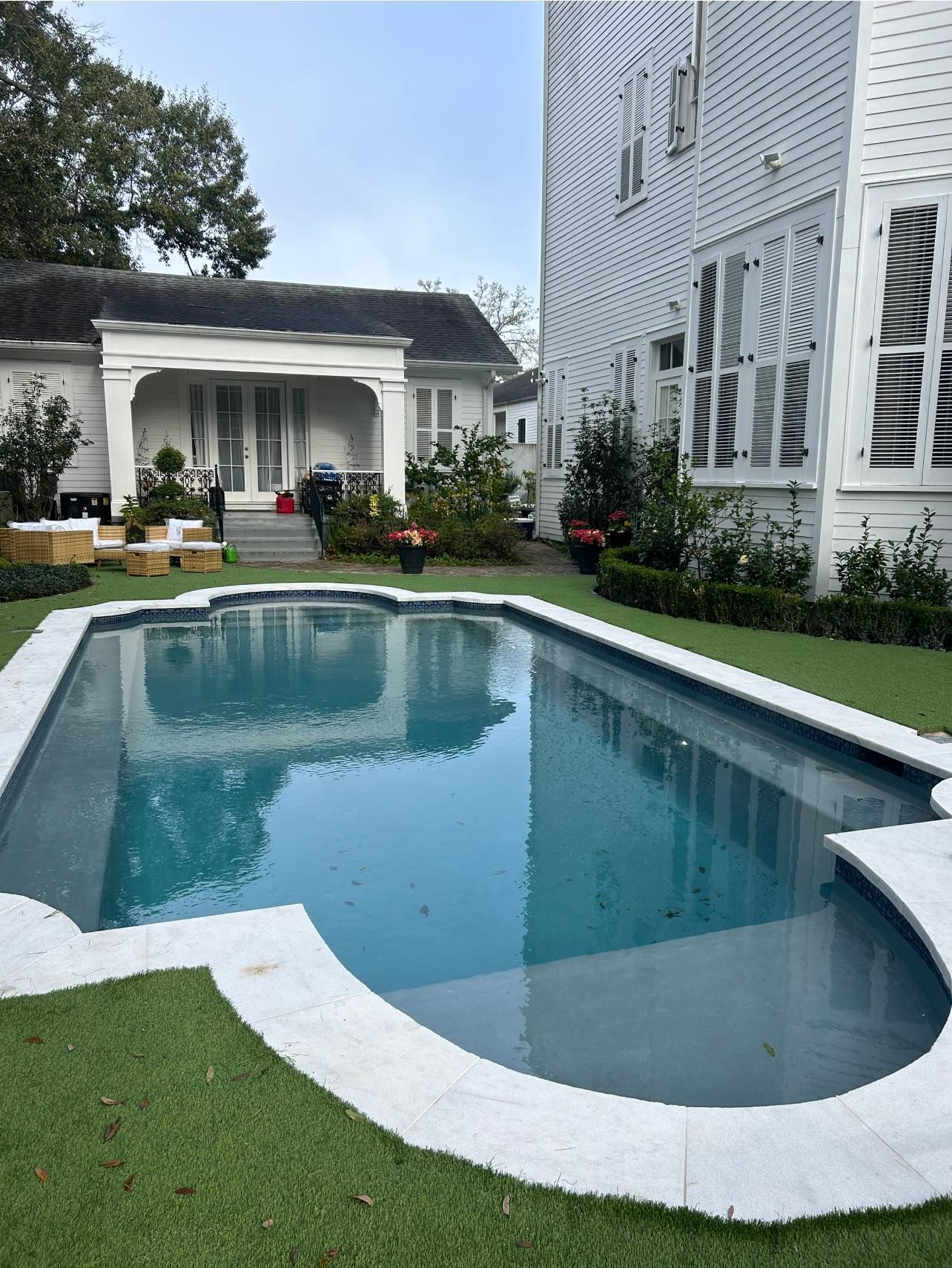 A large swimming pool is in the backyard of a house.