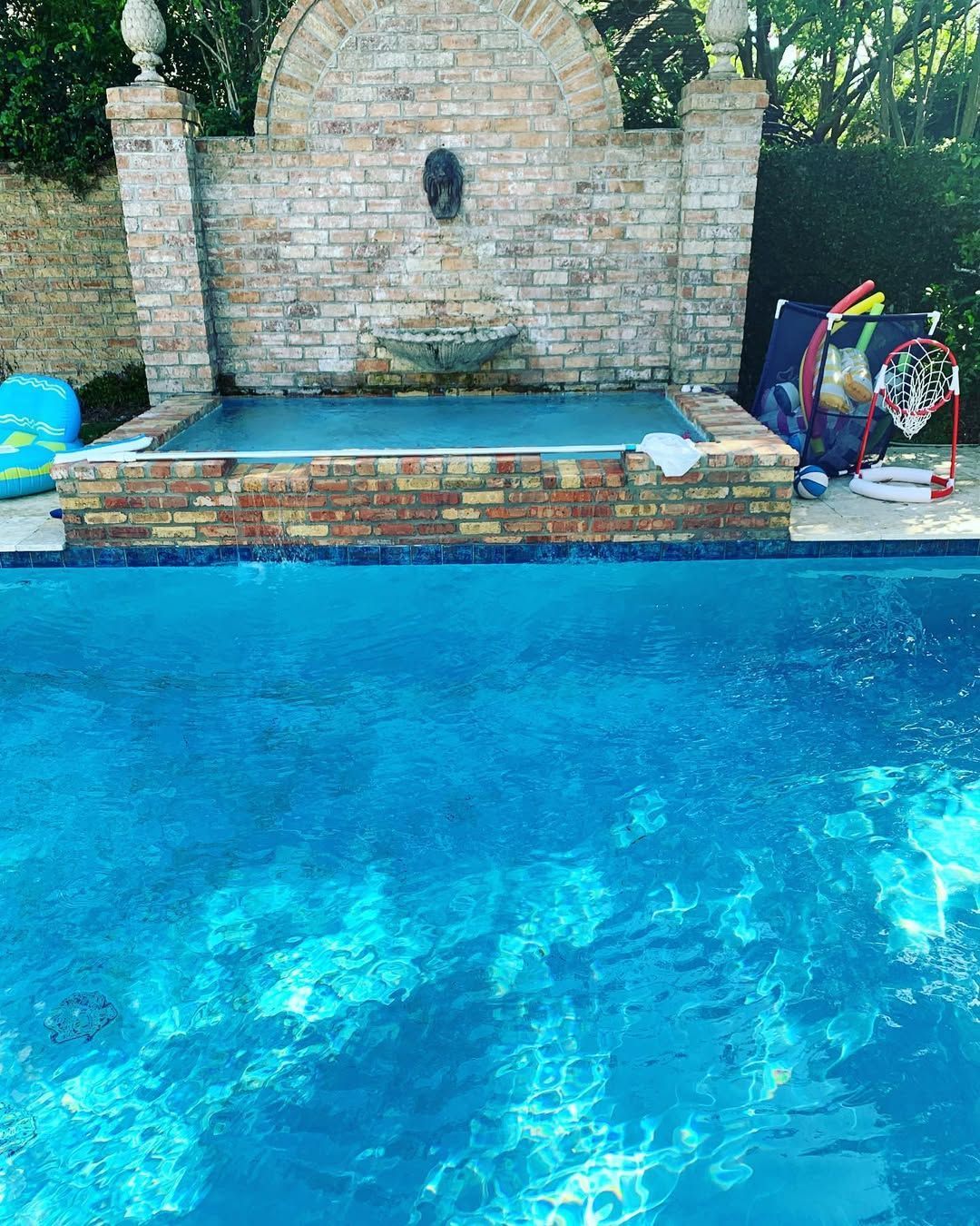 A large swimming pool with a fountain in the middle of it.