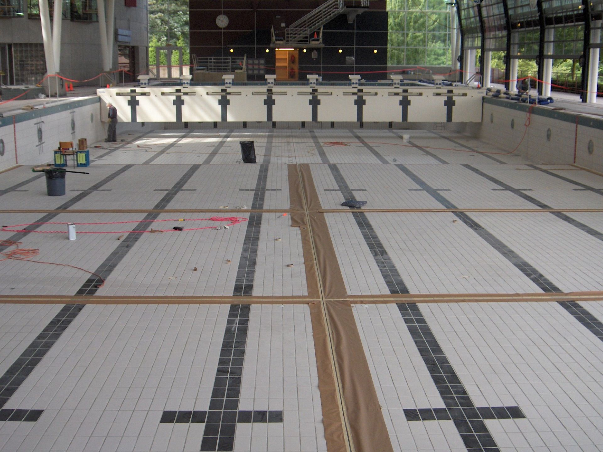 A man is taking a sample of water from a swimming pool.