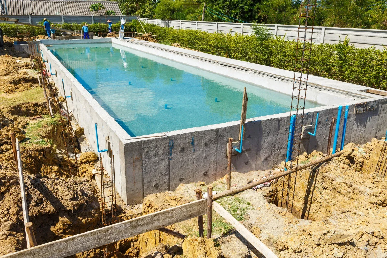 A large swimming pool is being built in a backyard.