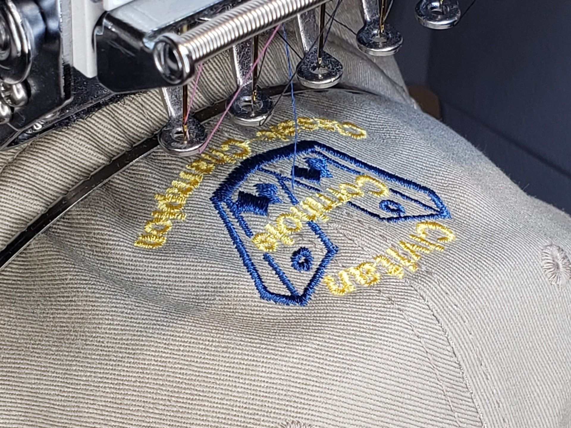 A person is using a sewing machine to embroider a logo on a hat.