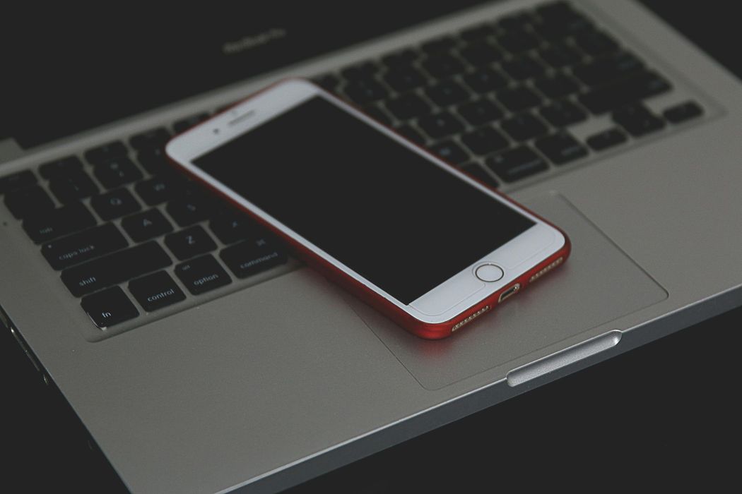 A cell phone is sitting on top of a laptop keyboard.