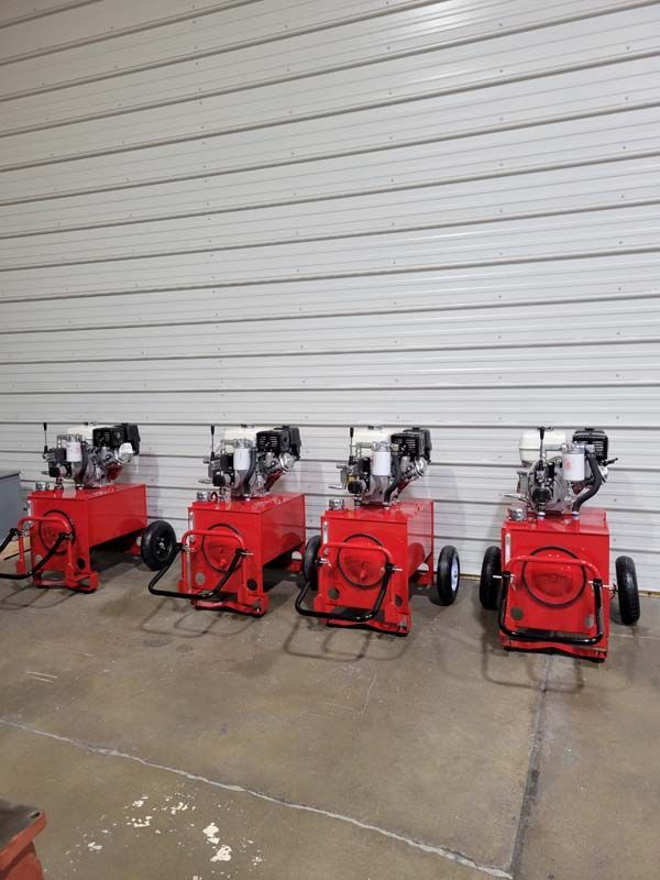 a row of red hydraulic pumps are lined up against a white wall