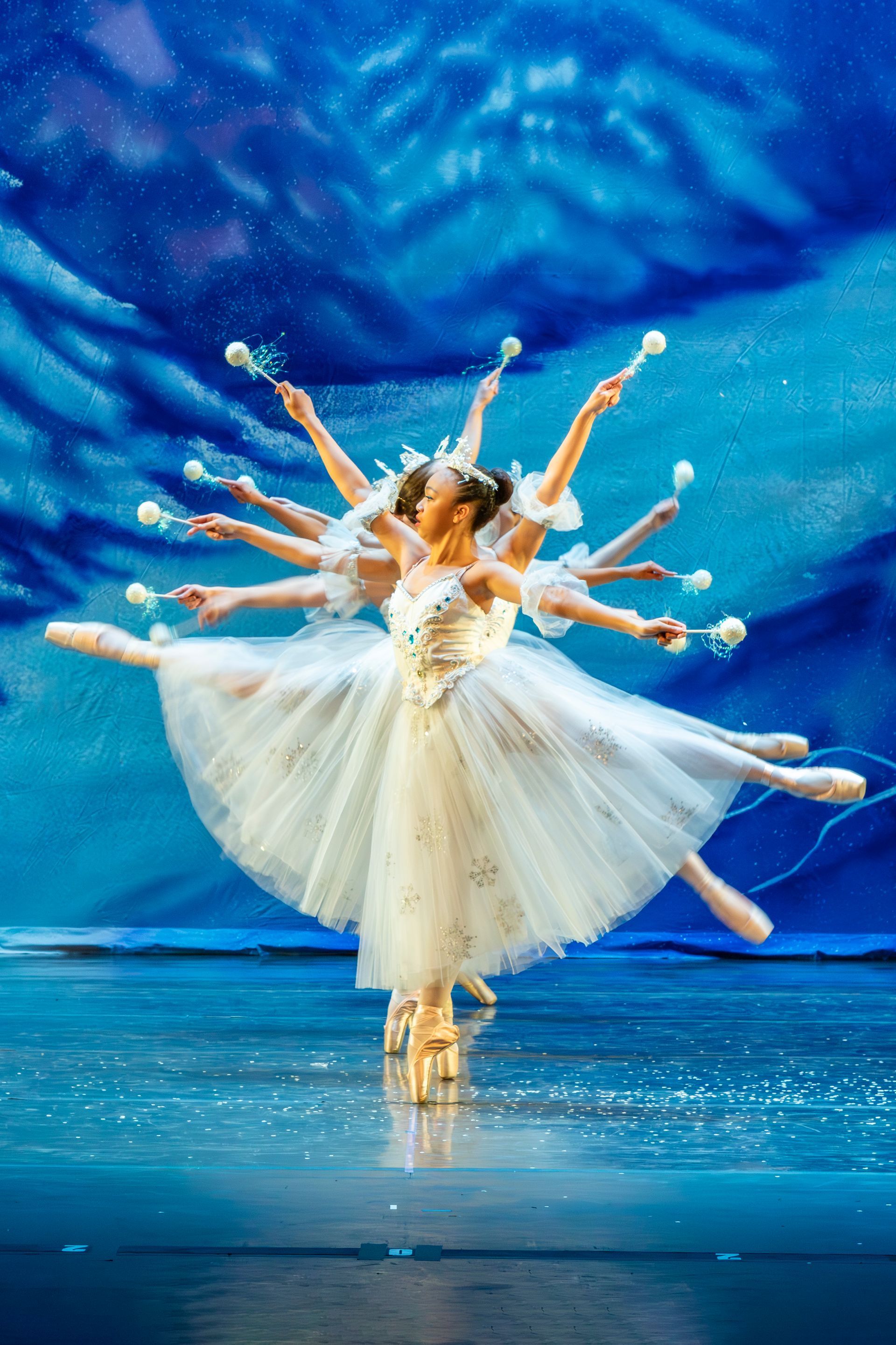 Three ballerinas in blue tutus are jumping in the air