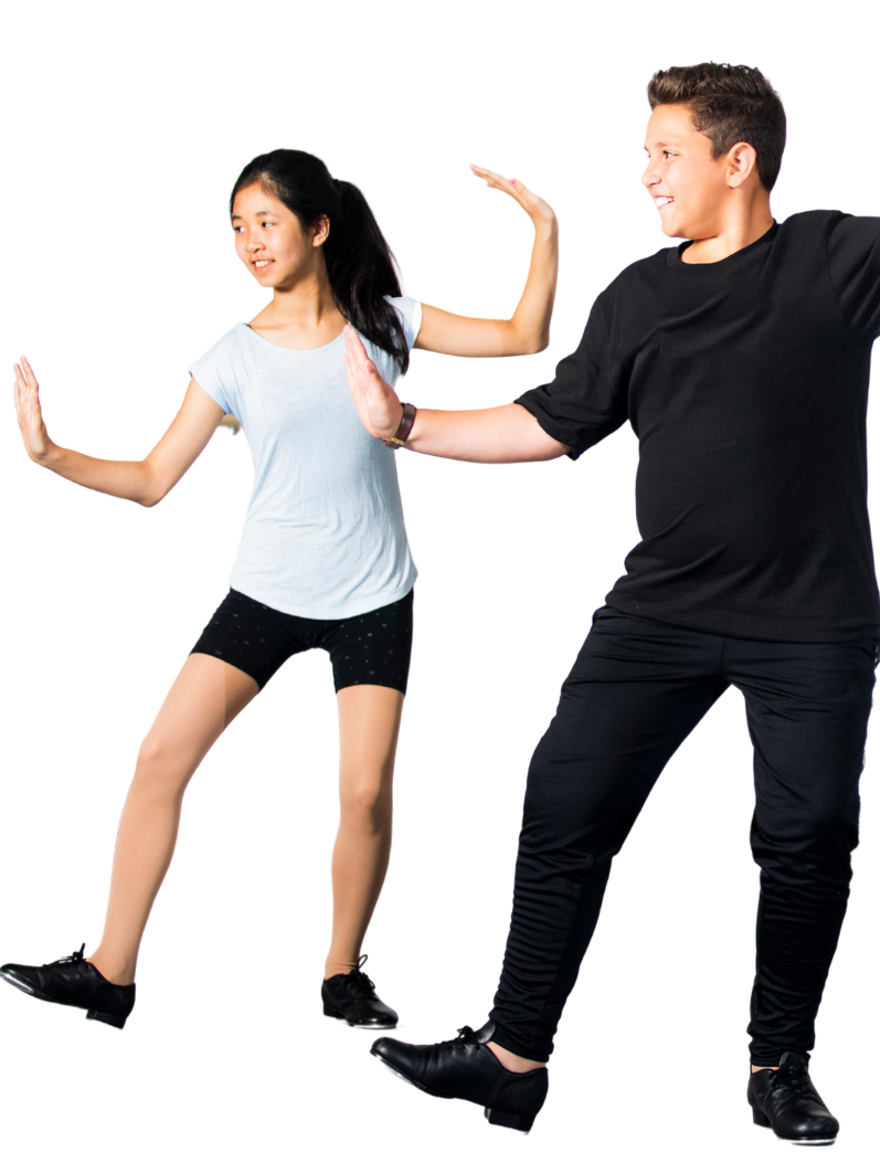Two young dancers, a girl and a boy, in black tap shoes and athletic clothing, performing on a white backdrop. The girl wears a light blue top and black shorts. The boy wears a black shirt and pants.