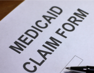 A Medicaid claim form sits on a surface with a black pen resting nearby.