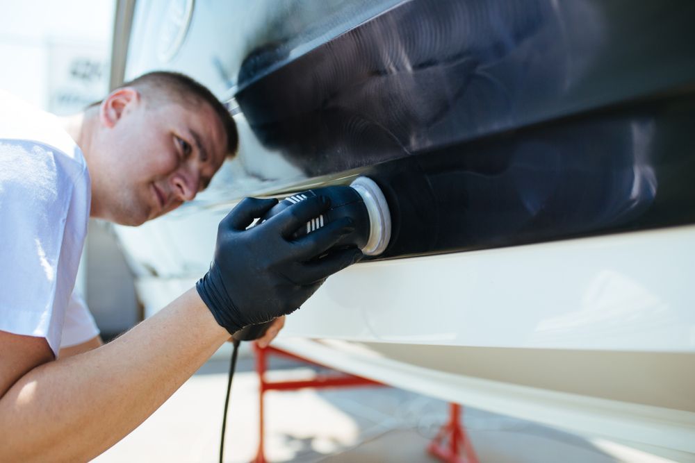 Man in Gloves Polishes a Boat Hull With a Power Buffer Outdoors — TrueGloss Elite Coatings In Wyong, NSW