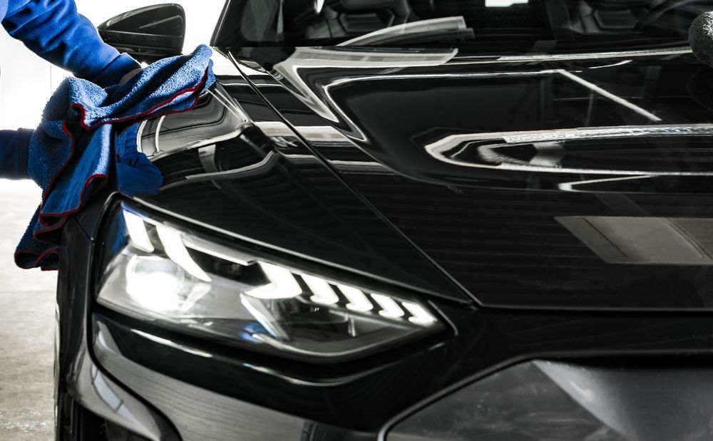 Person Polishing a Shiny Black Car With a Blue Microfibre Cloth — TrueGloss Elite Coatings In Newcastle, NSW