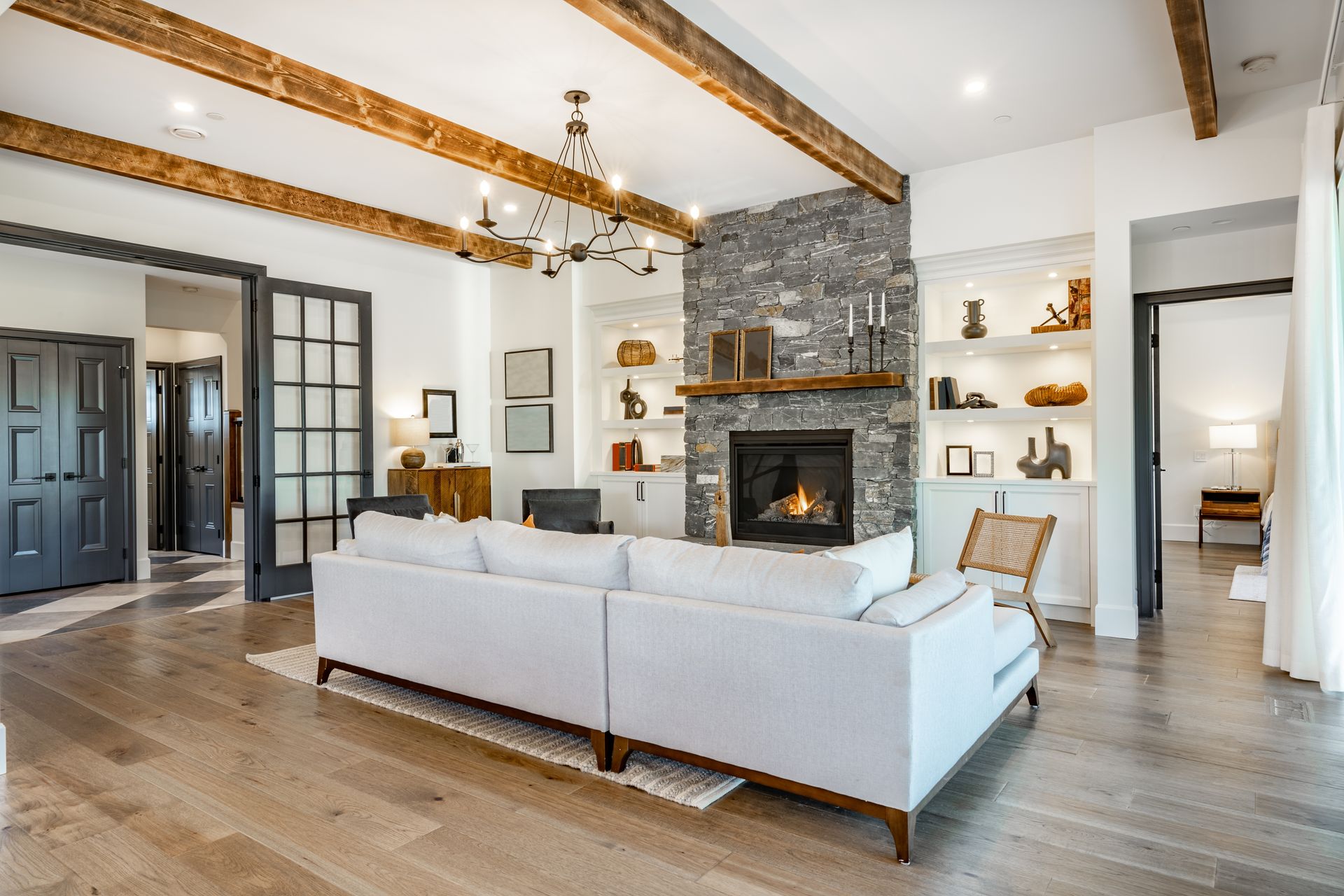 Bright living room with exposed beams, stone fireplace, and a white sectional sofa