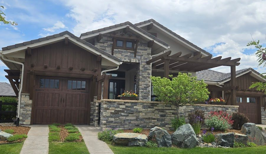 Modern stone-and-wood house exterior with garage, front porch, and landscaped yard