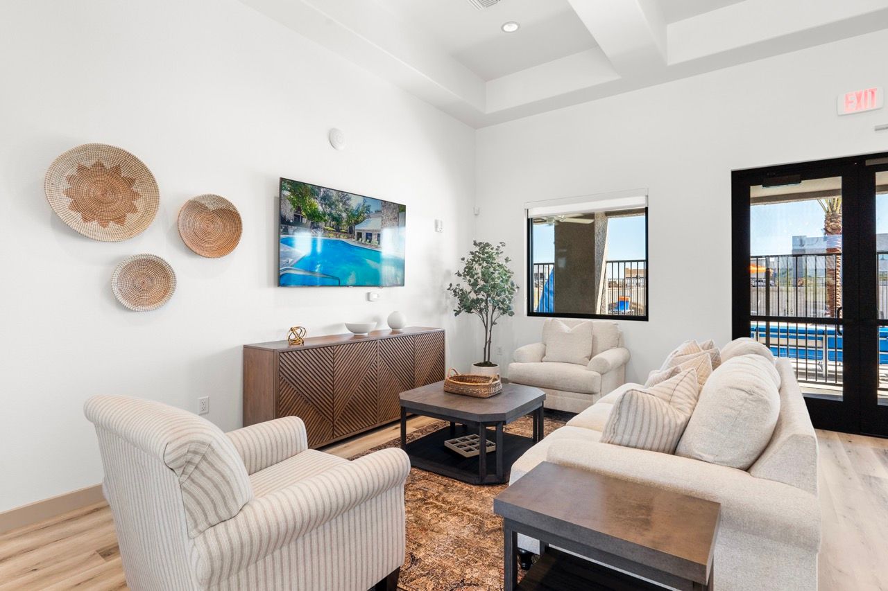 Bright living room with beige sofas, an armchair, coffee table, TV, and glass doors to a pool area.