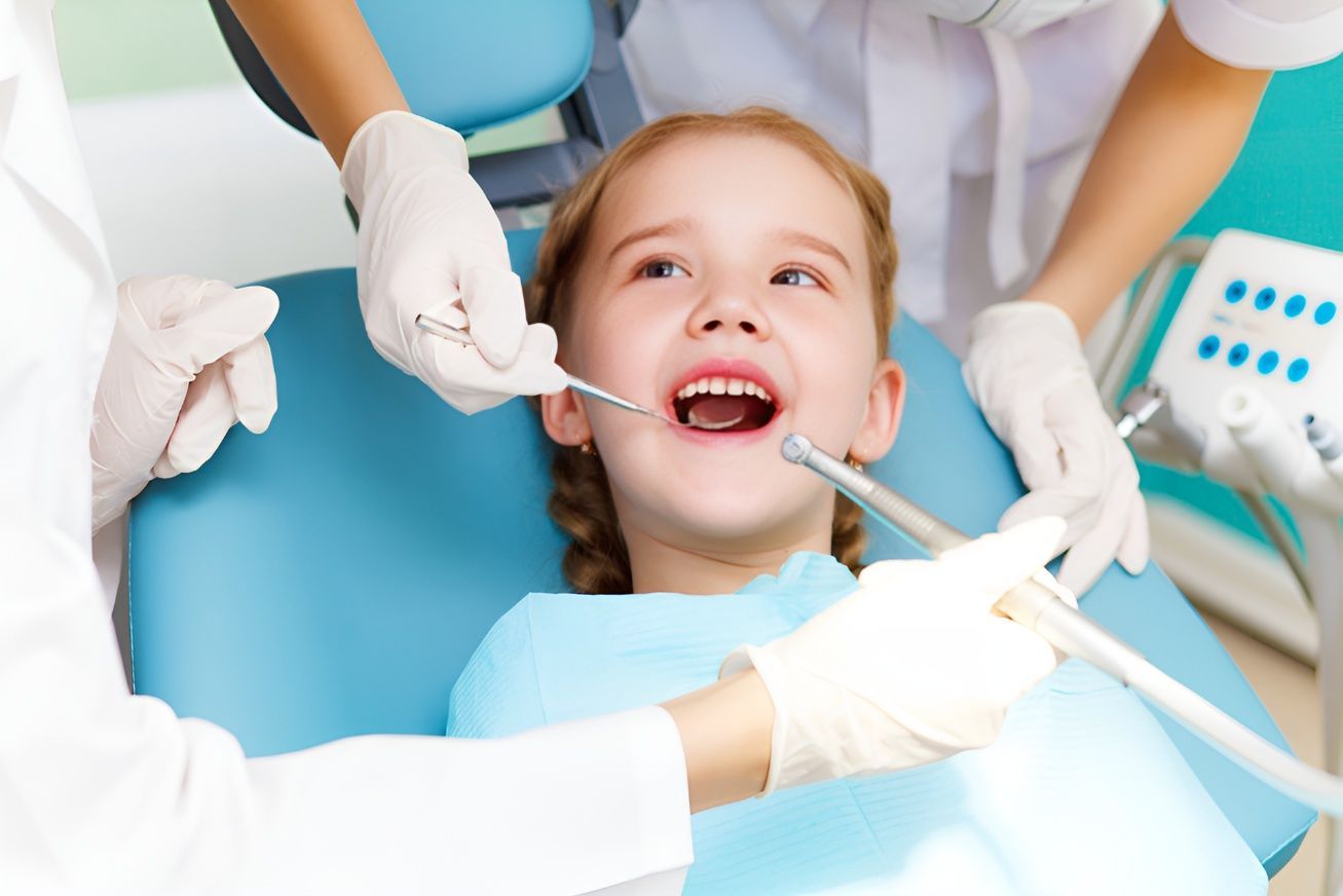 A Little Girl is Getting Her Teeth Examined by a Dentist — Tweed Banora Dental In Tweed Heads South, NSW