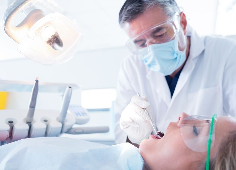 A Dentist is Examining a Patient's Teeth in a Dental Office — Tweed Banora Dental In Tweed Heads South, NSW