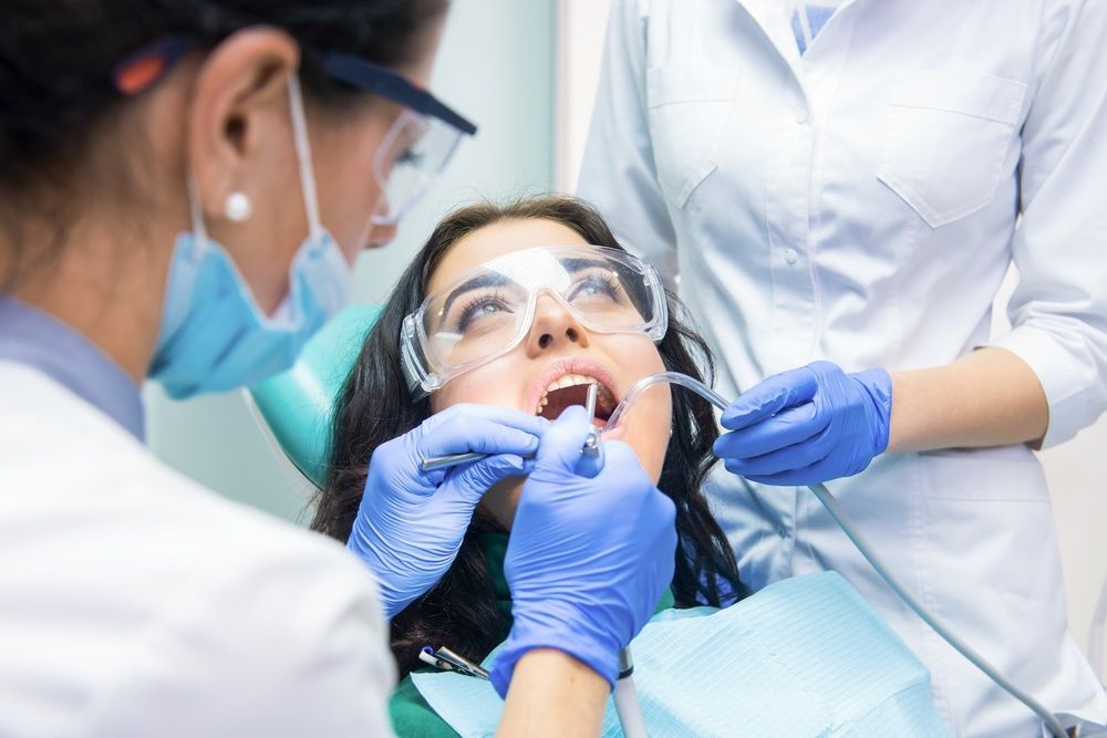 A Woman is Getting Her Teeth Examined by Two Dentists — Tweed Banora Dental In Tweed Heads South, NSW