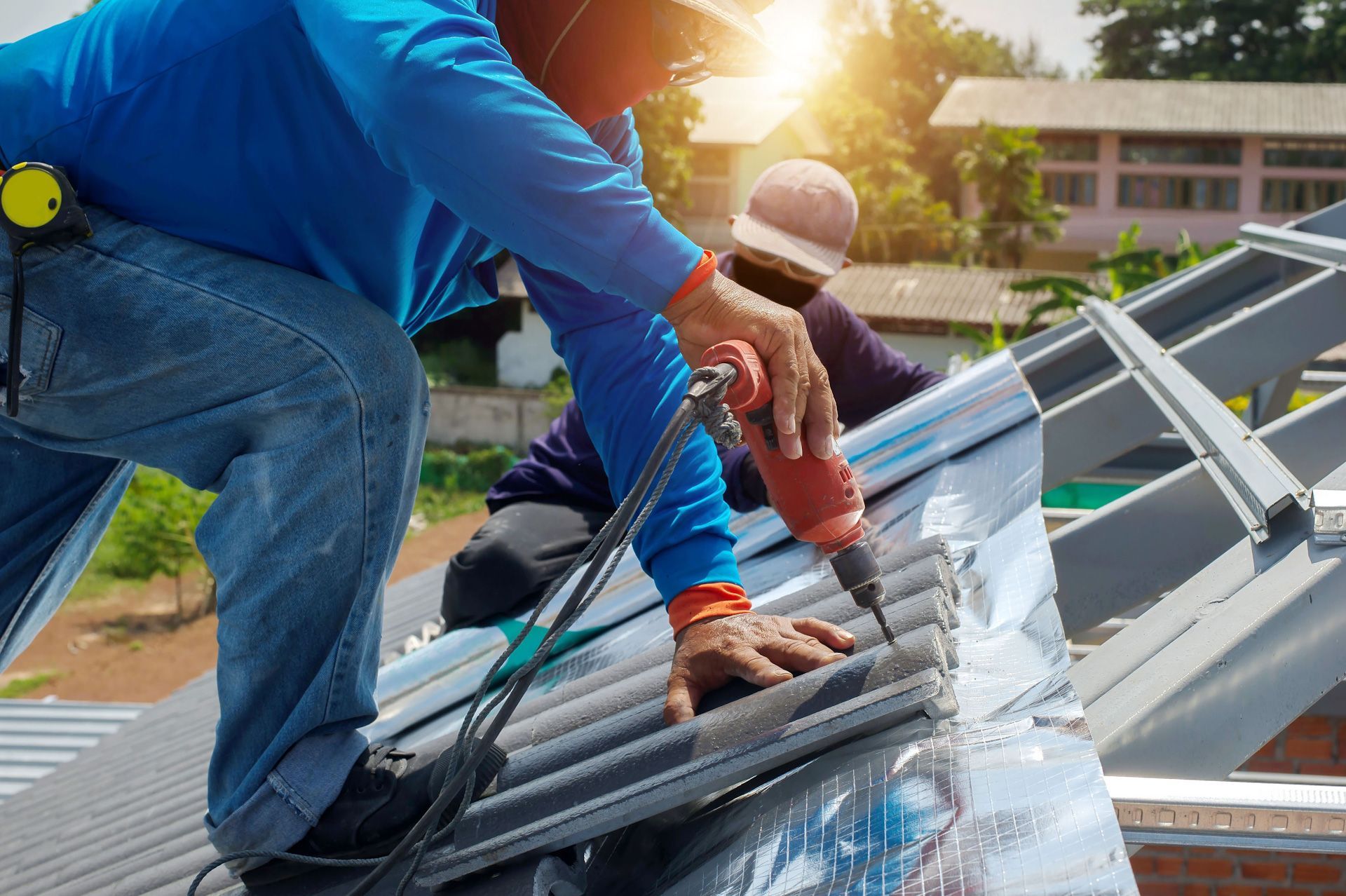 A man is working on a roof with a drill.