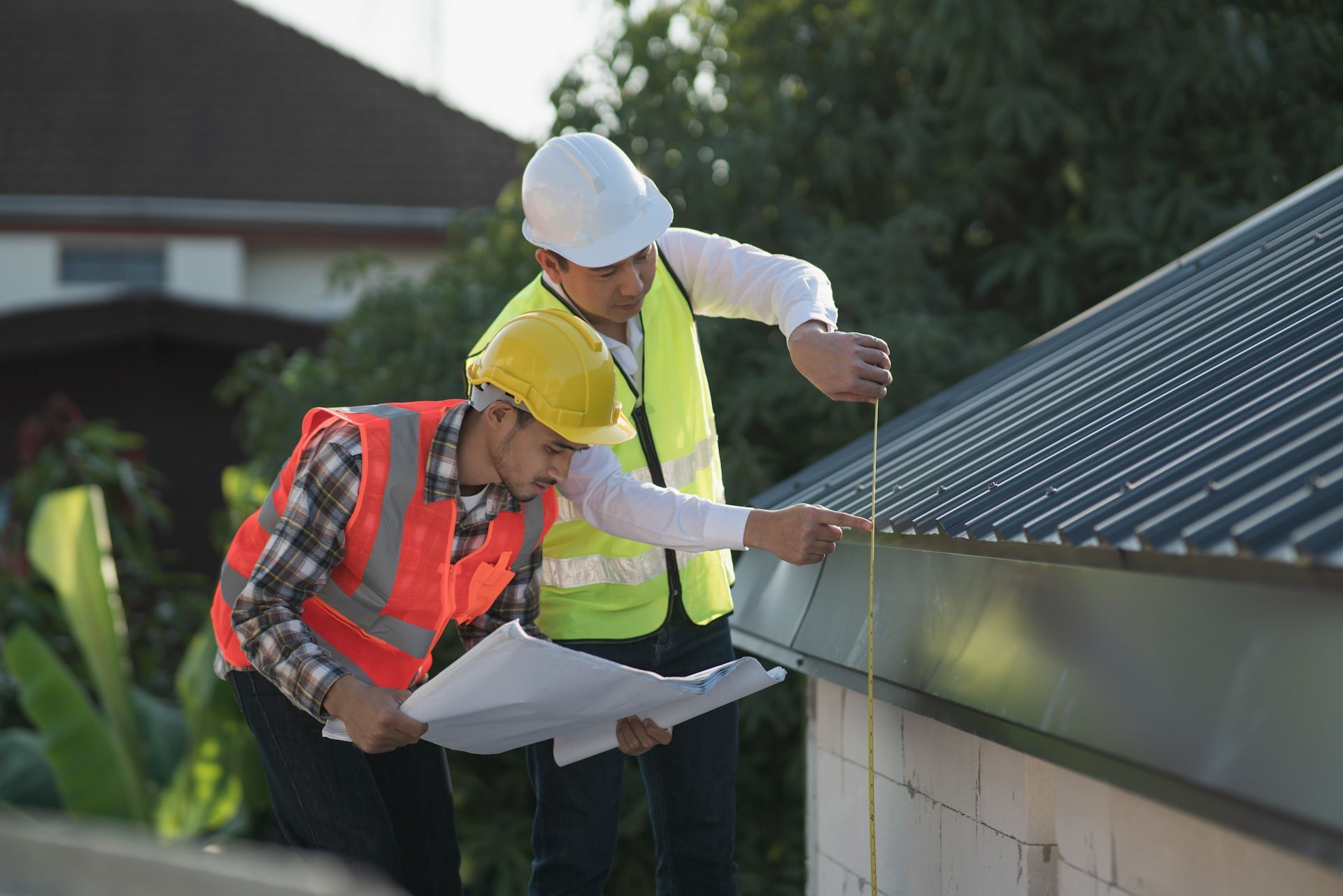 Two construction workers are measuring the roof of a house.