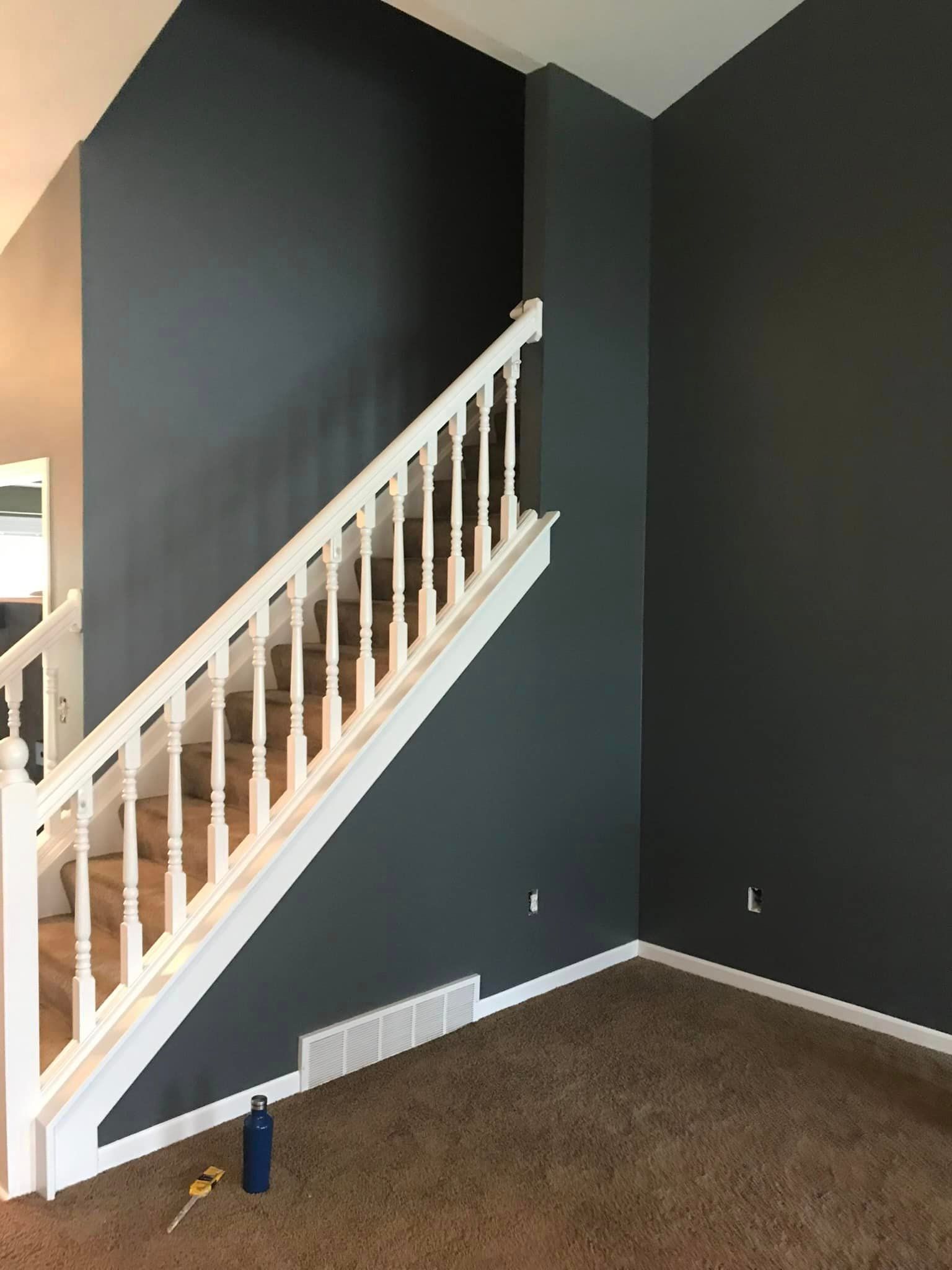 An empty living room with stairs and a white railing.