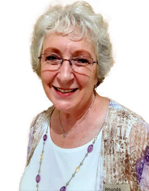 A woman wearing glasses and a purple necklace is smiling for the camera.