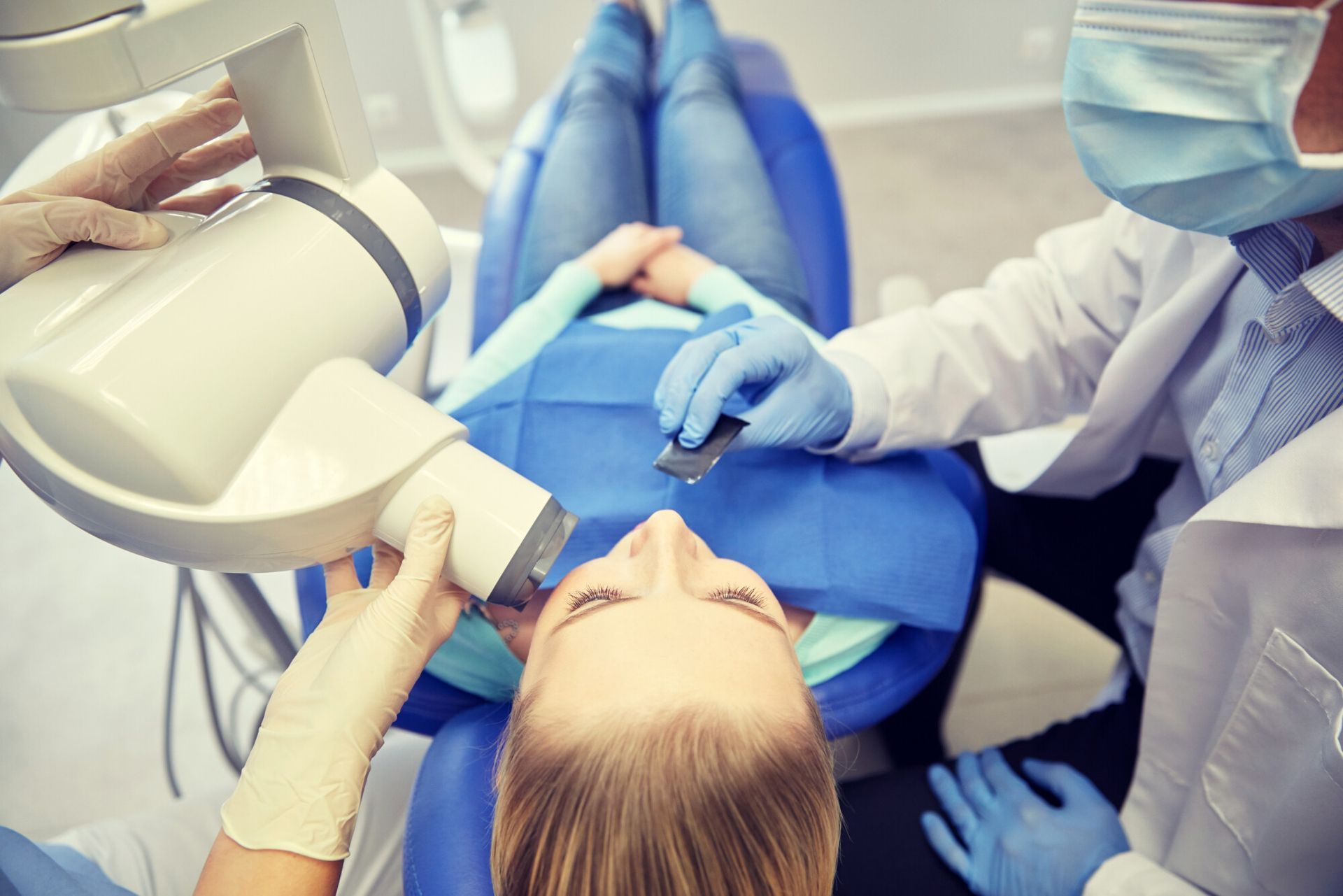 a woman is laying in a dental chair while a dentist examines her teeth .