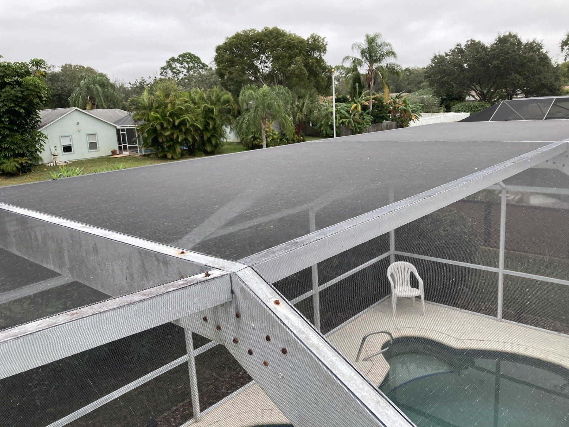 A roof of a house with a screened in area and a pool.