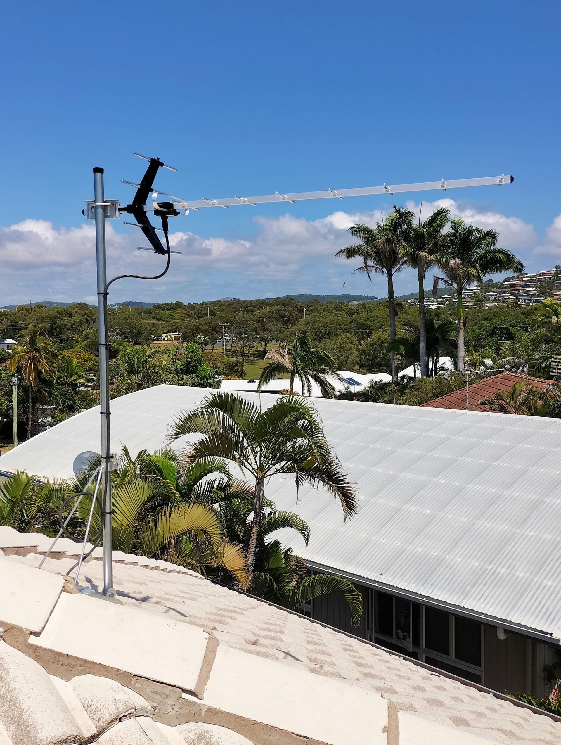 Antenna on a roof over looking mountains and a roof — Coastline Installations In Emu Park, QLD